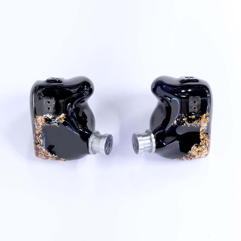 Moritz Audio ENZO Flagship In Ear Monitors. Pair of glossy black in-ear monitors with gold flake accents and silver nozzles, on white background.